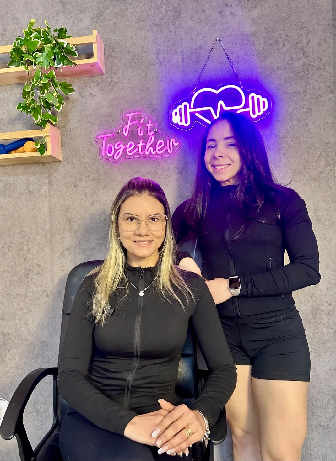 As duas fundadoras da Fit Together em frente ao letreiro neon da marca